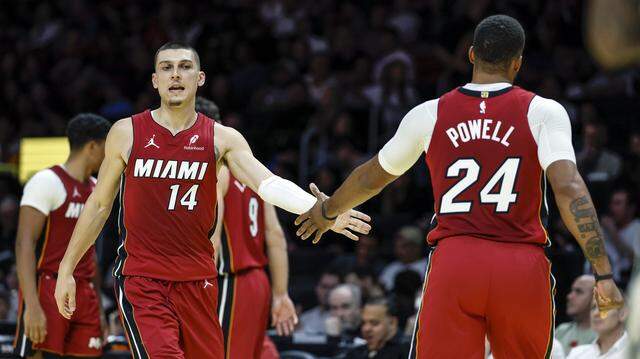 Miami Heat guards Tyler Herro (14) and Norman Powell (24) greet each other on the court during their NBA basketball game against the Milwaukee Bucks at Kaseya Center in Miami on November 26, 2025.